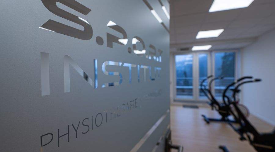 Nahaufnahme einer Glastür zum Trainingsraum mit Geräten im Hintergrund