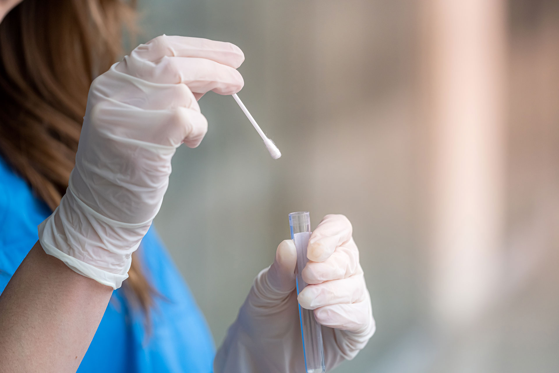 Labormitarbeiterin mit Wattestäbchen und Reagenzglas in der Hand